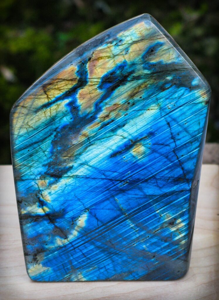 Polished labradorite crystal showcasing vibrant blue, gold, and green flashes, ideal for enhancing intuition, spiritual protection, and energy balance.